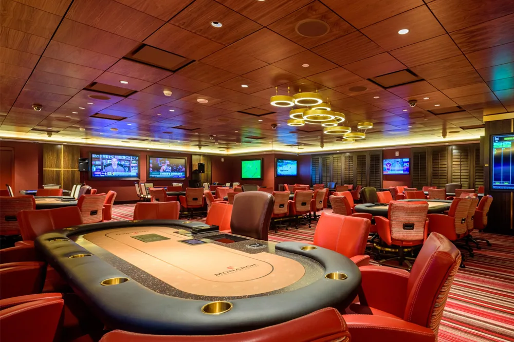 interior of a casino with poker tables and lots of tvs