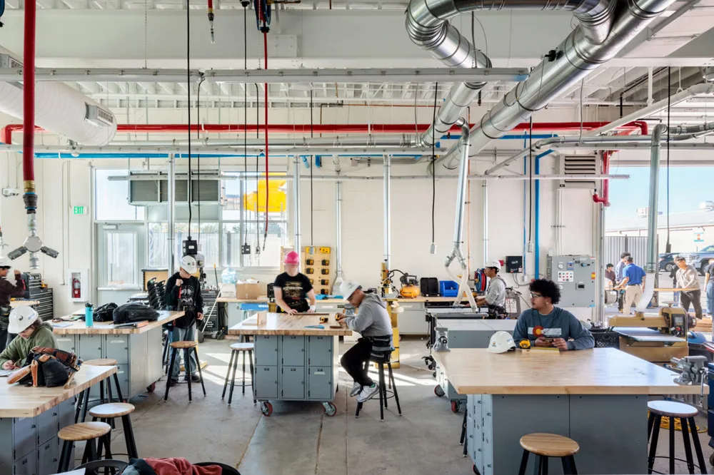 inside of school shop room, lots of tables with stool and people working on projects